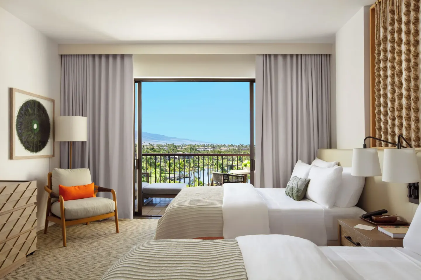 Two-bed guest room with balcony and distant water view at Mauna Lani.