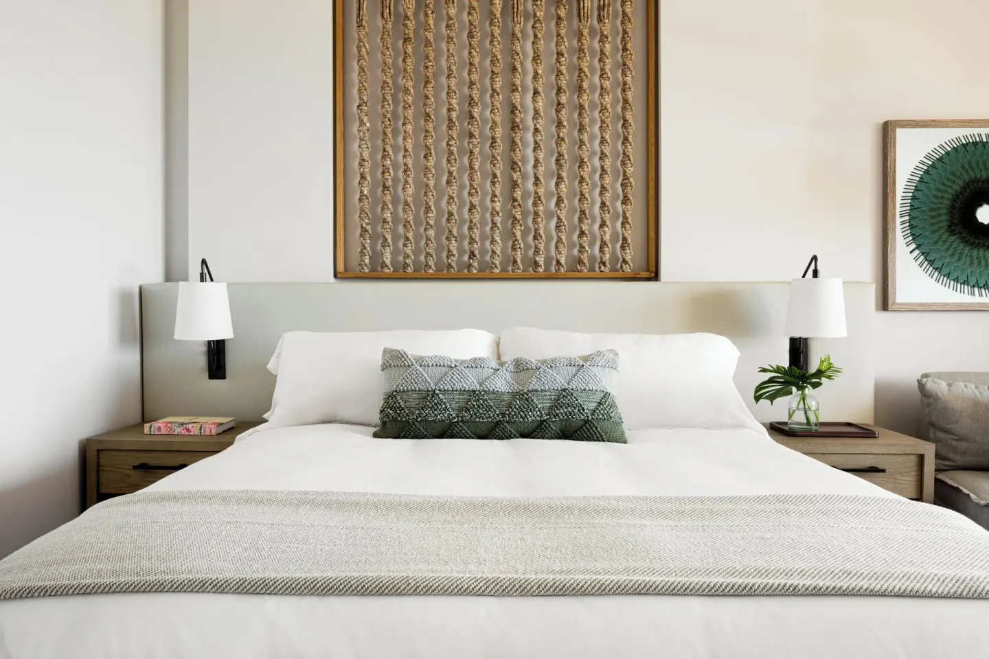 Close view of a king bed with lamps and woven wall art at Mauna Lani.