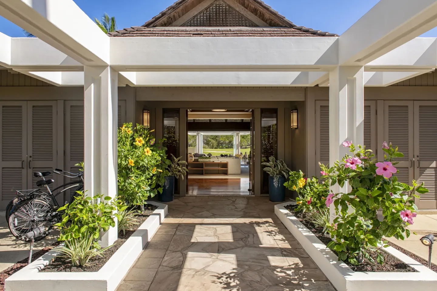 Resort entry walkway with hibiscus plants and open doors at Mauna Lani.