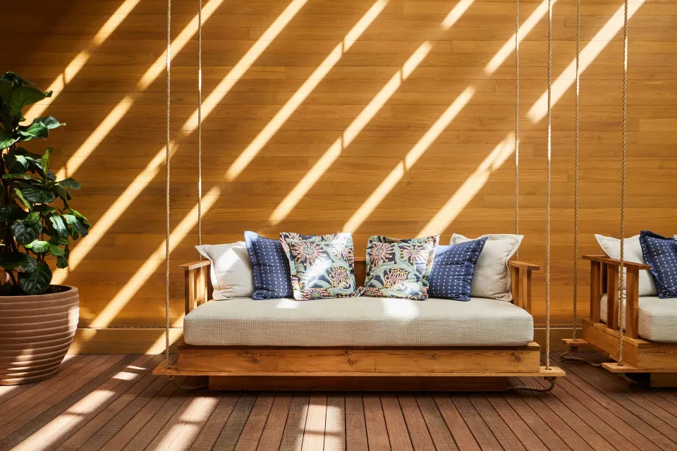 Rope-hung daybed with patterned pillows against a wood wall at Mauna Lani.