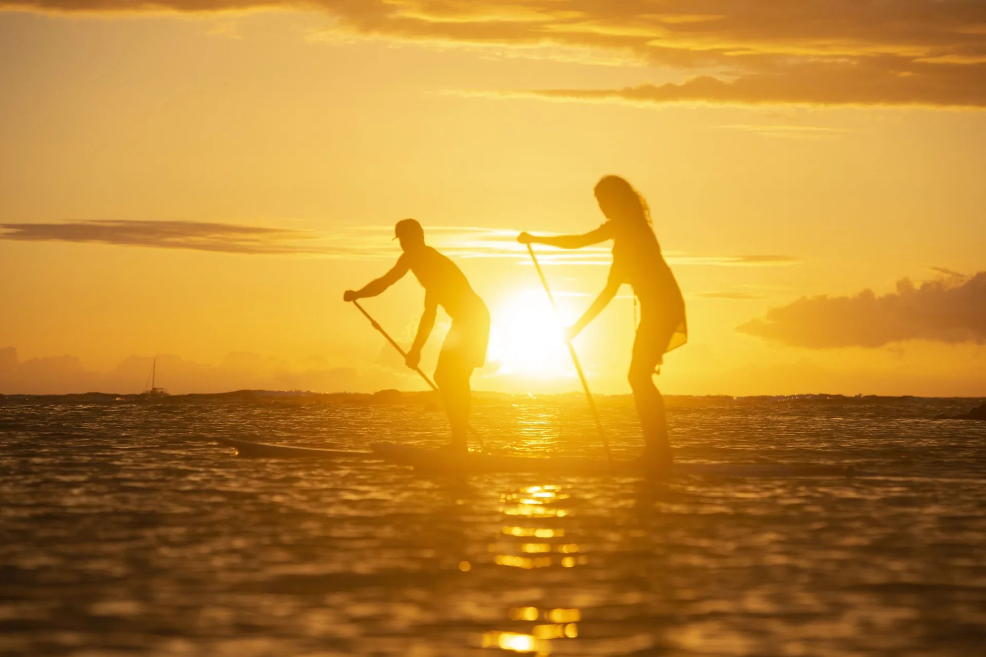 Two paddleboarders silhouetted on the ocean at sunset at Mauna Lani.