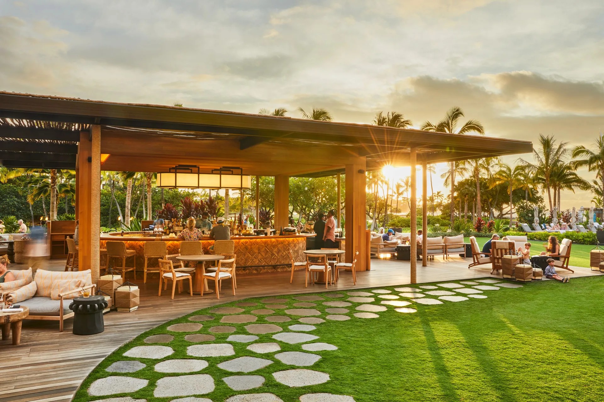 Open-air bar with lounge seating and sunset light on the lawn at Mauna Lani.