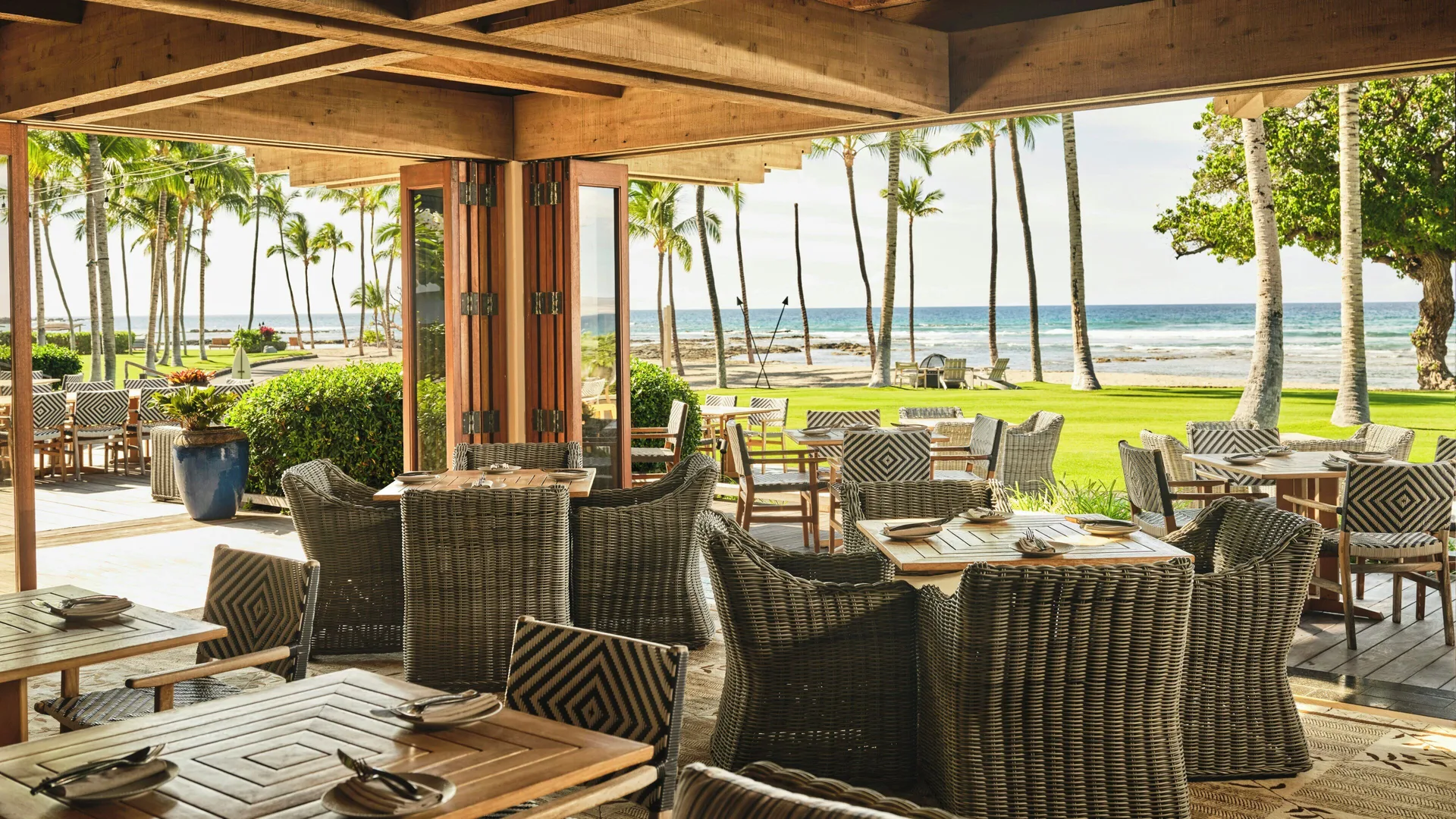 Open-air dining room with set tables and ocean views at Mauna Lani.