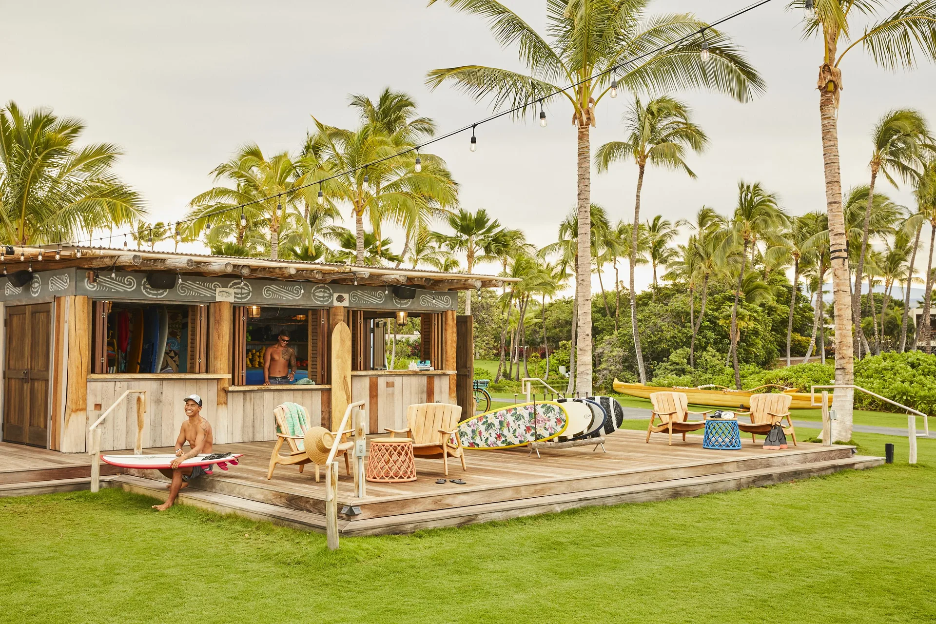 Surf shack deck with boards, chairs and palms on the lawn at Mauna Lani.