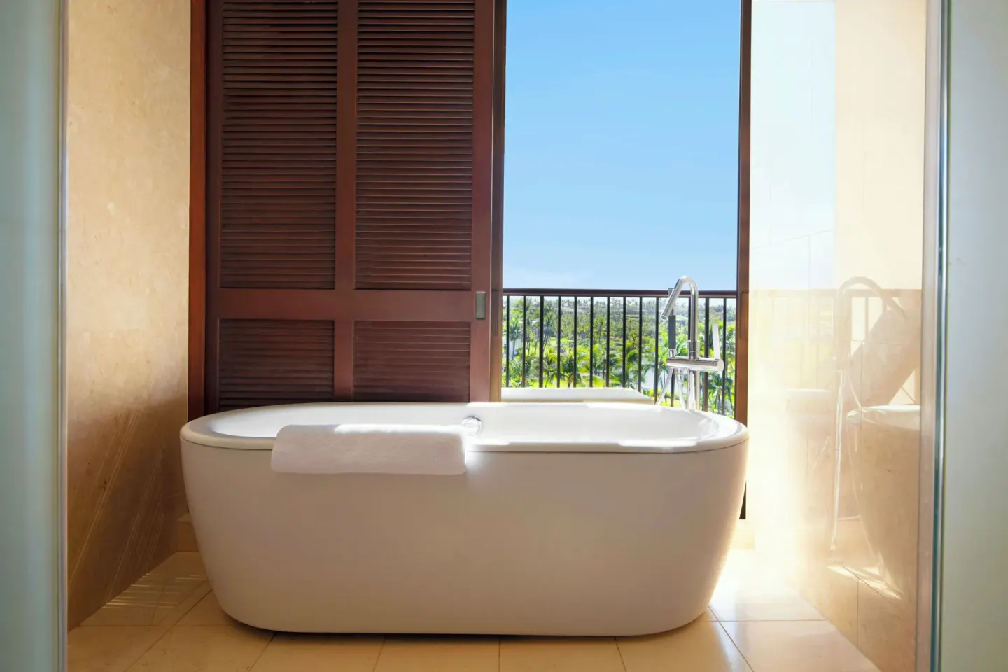 Freestanding bathtub with balcony and ocean view in a Deluxe Suite at Mauna Lani.