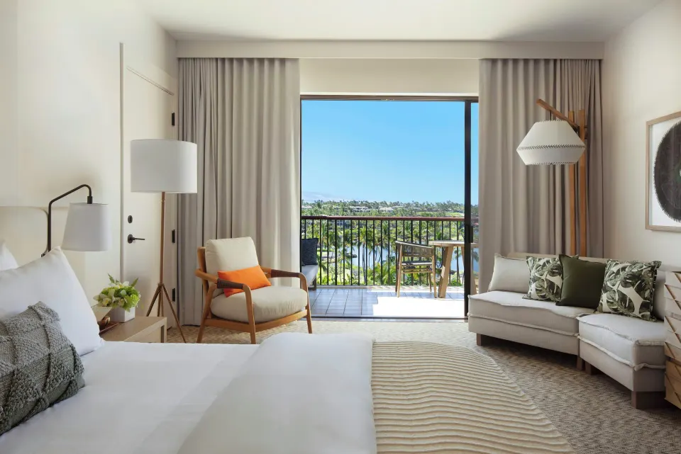 Ocean View room at Mauna Lani with king bed, sofa, seating, and balcony facing palm trees and water.