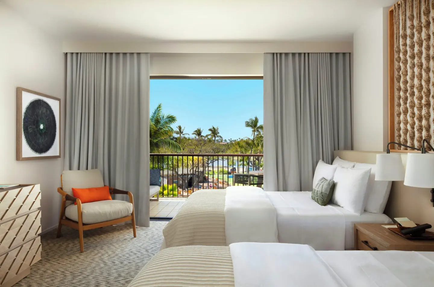 Ocean View room at Mauna Lani with two beds, armchair, dresser, and balcony framed by curtains.