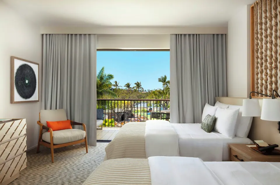 Ocean View room at Mauna Lani with two beds, armchair, dresser, and balcony framed by curtains.