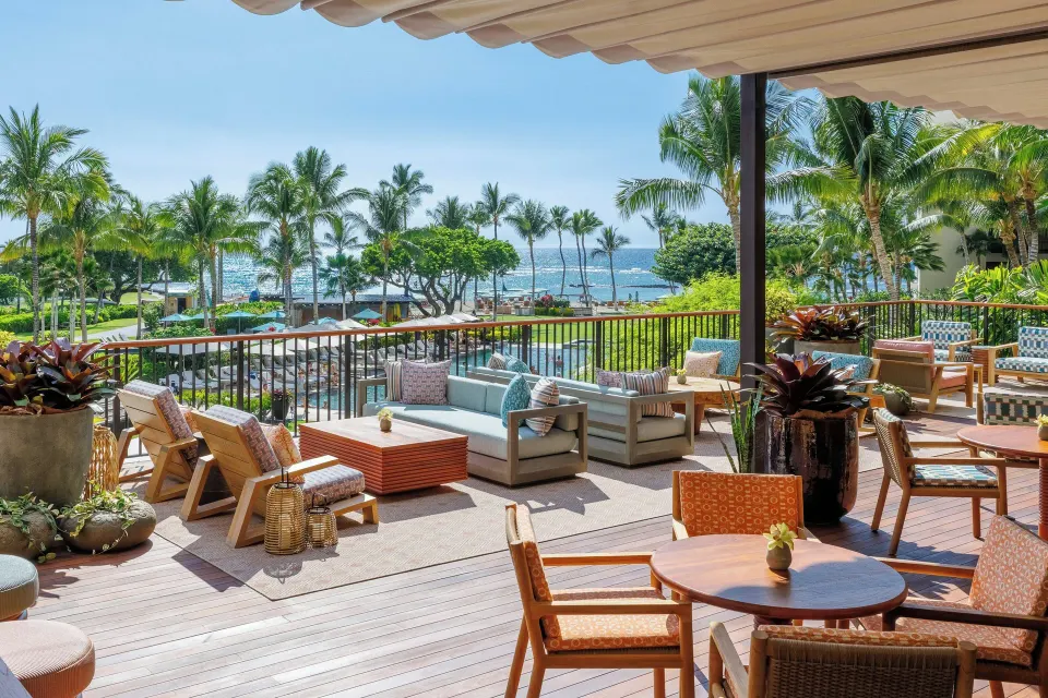 Oceanfront club lounge terrace seating at Mauna Lani with pool, palms, and ocean beyond.