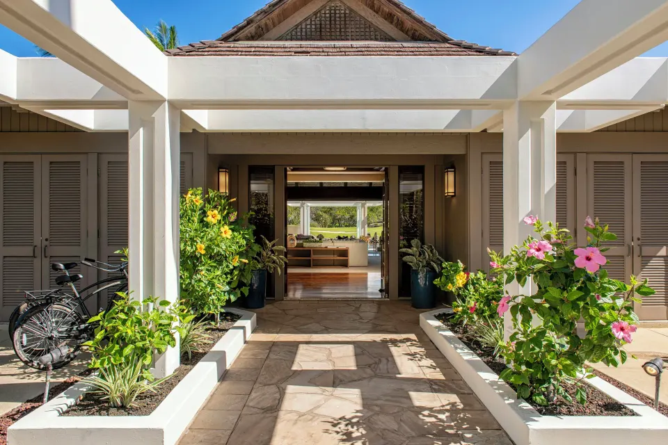 Entrance courtyard to an ocean-view villa at Mauna Lani with flowers, bikes, and open doors.