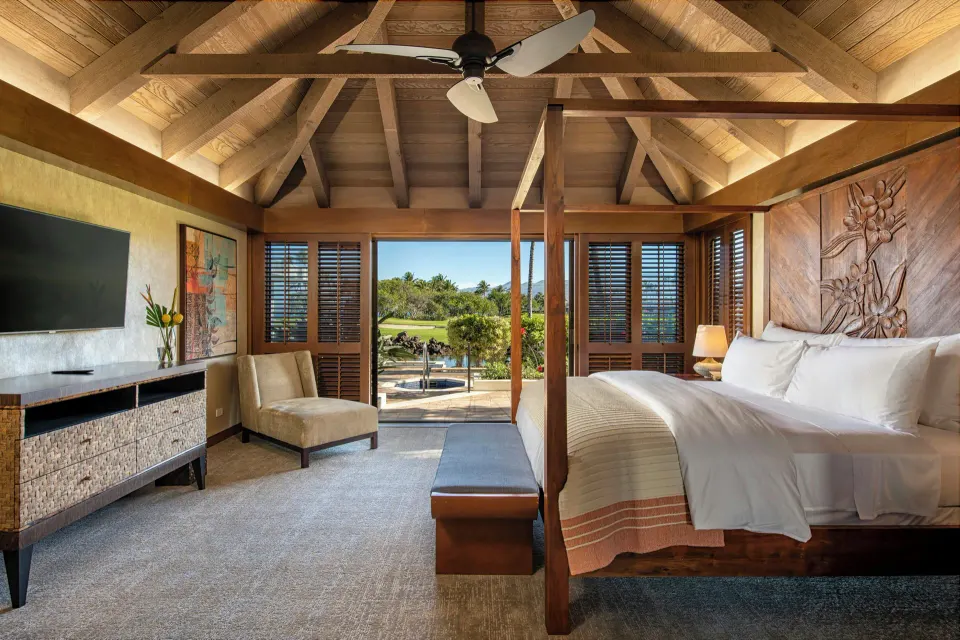 King bed in an ocean-view villa bedroom at Mauna Lani with open doors to the terrace.