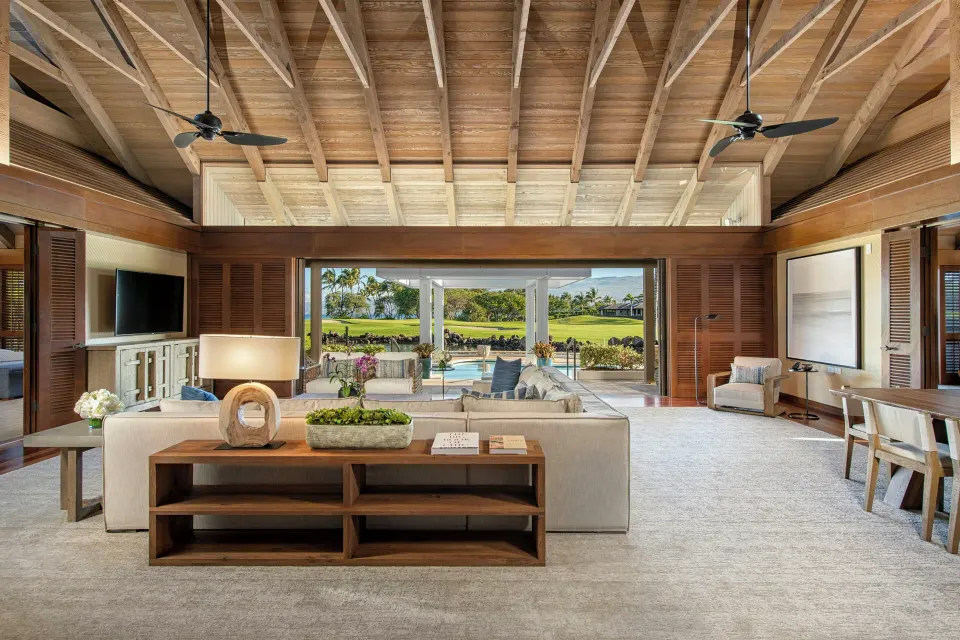 Spacious villa living area at Mauna Lani opening to a pool and lawn with ocean beyond.