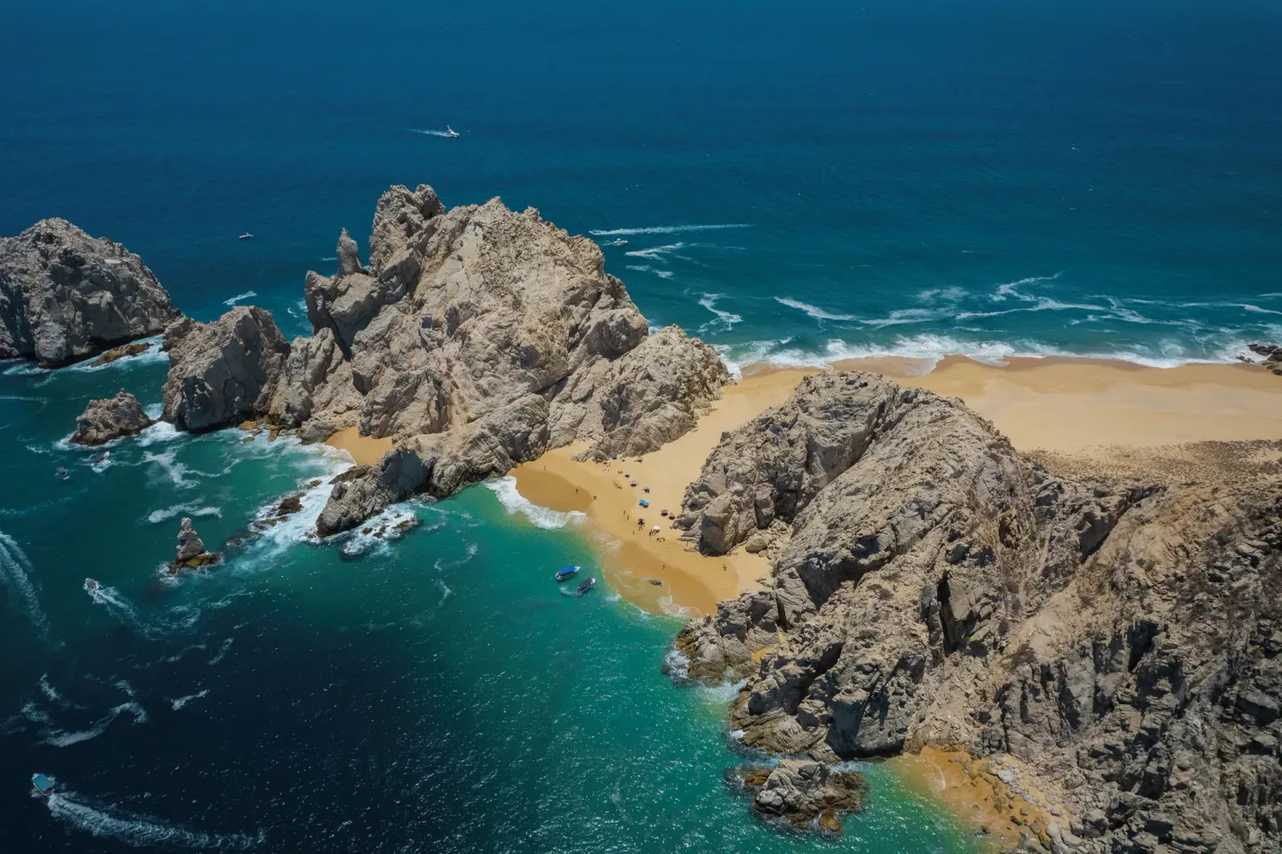 Aerial coastline view with rocky cliffs, sandy beach, and blue water near ME Cabo.