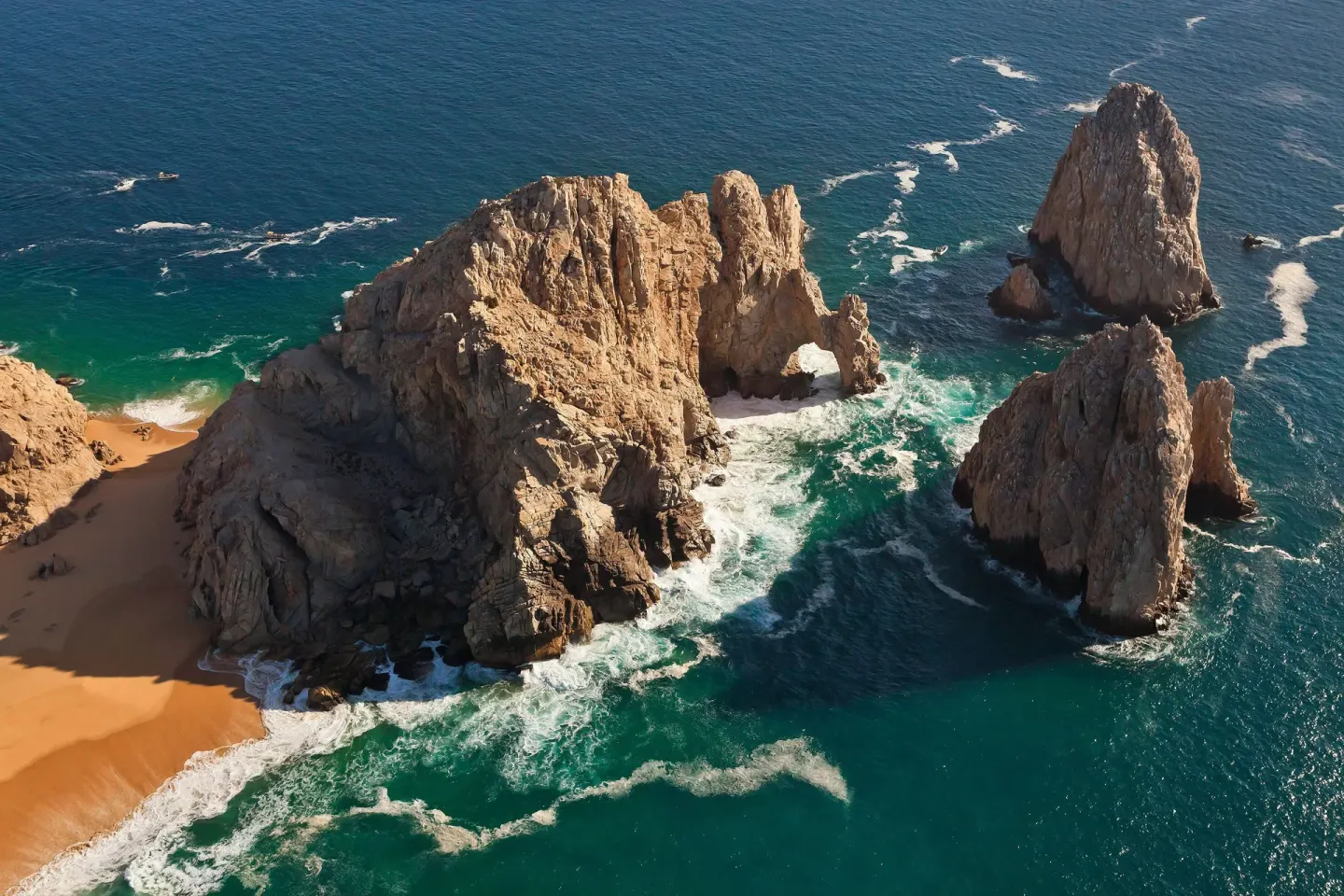 Aerial view of rocky sea arches and turquoise surf near ME Cabo.