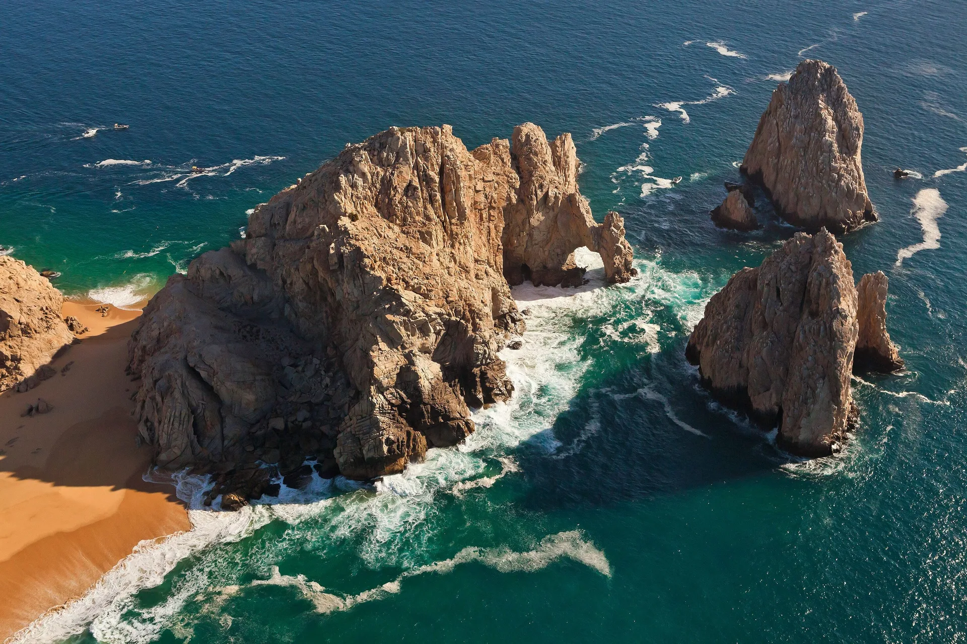 Aerial view of rocky sea arches and turquoise surf near ME Cabo.
