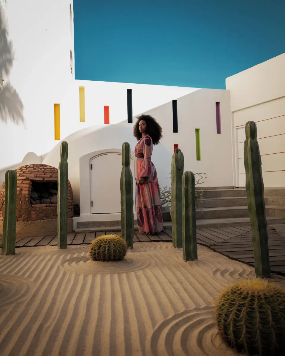 Cactus garden with sculpted sand, white walls, and a model at ME Cabo.