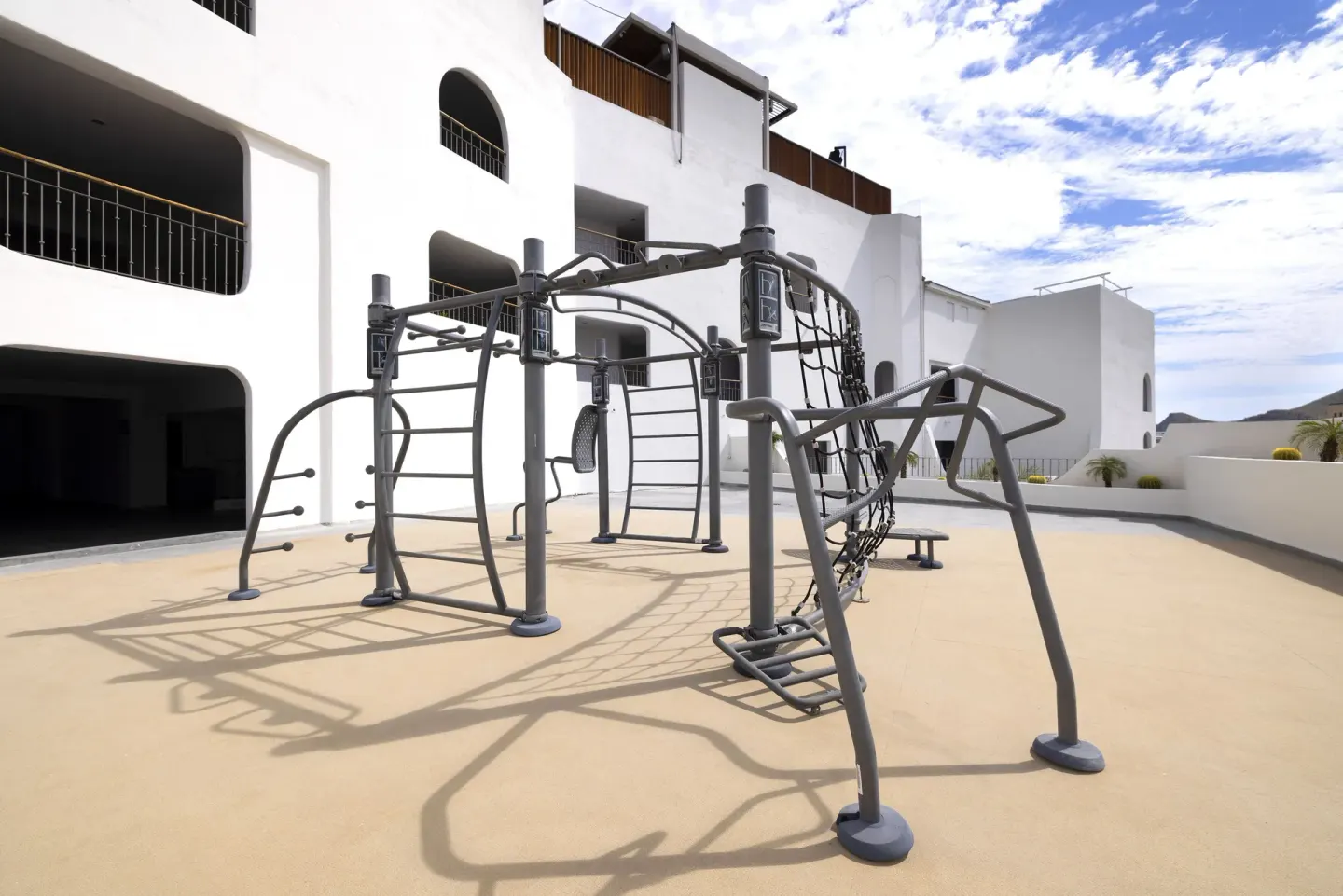 Outdoor exercise rig on a sunny terrace beside the resort building at ME Cabo.