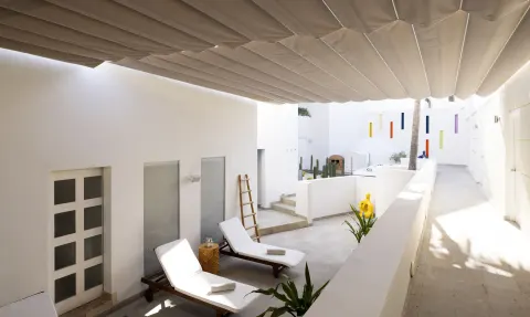 Shaded white courtyard with loungers and sculptural accents at ME Cabo.