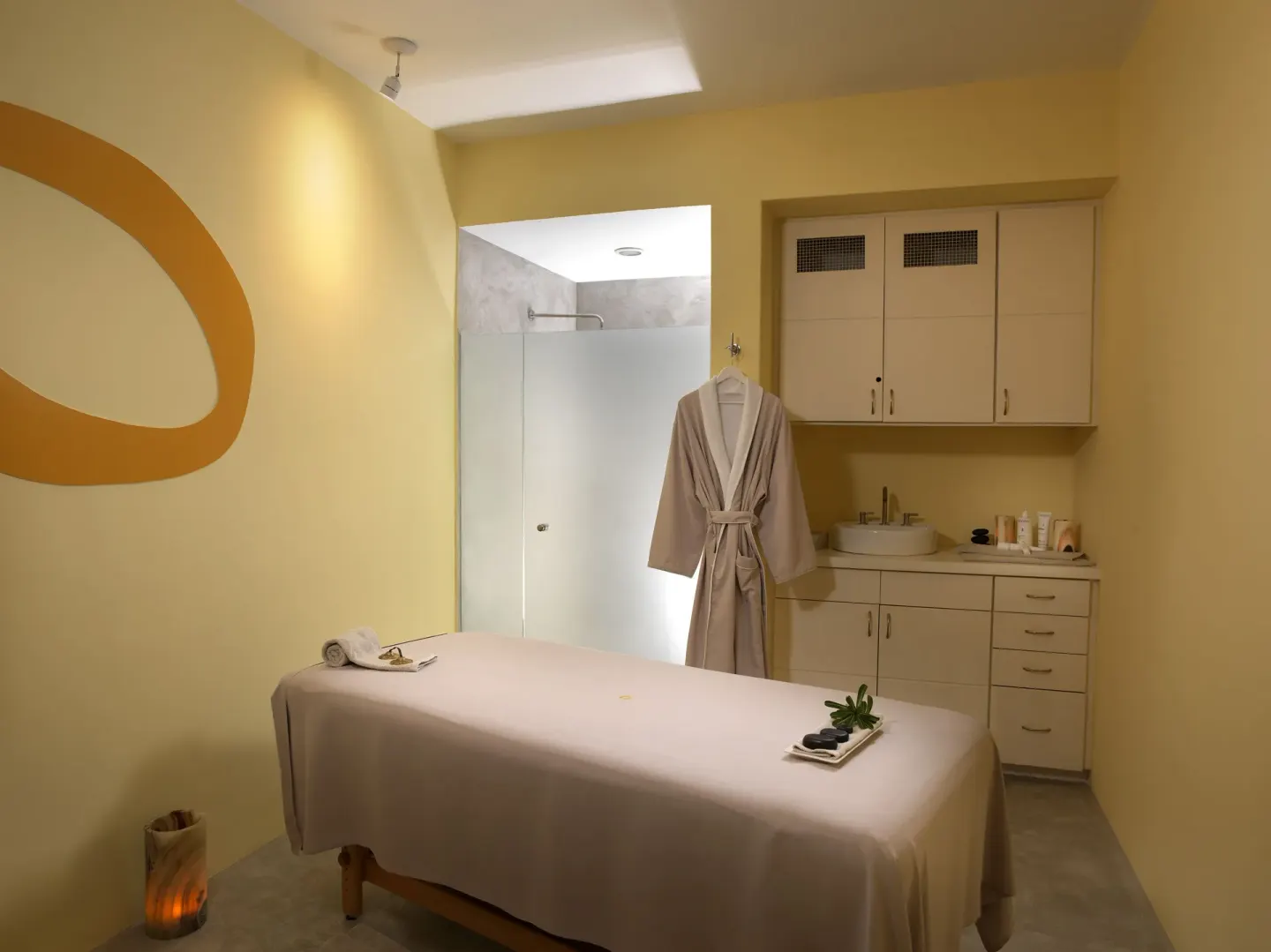 Spa treatment room with massage table, robe, shower, and vanity at ME Cabo.