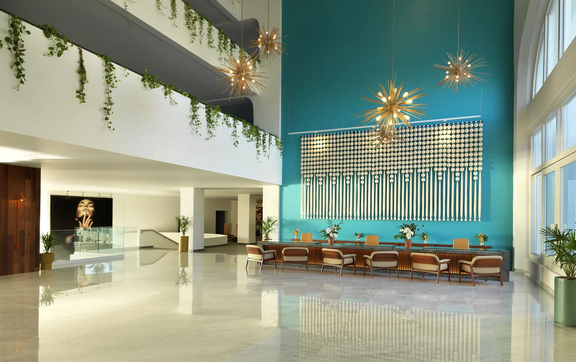 ME Cabo lobby with a turquoise feature wall, pendant lights and lounge chairs.