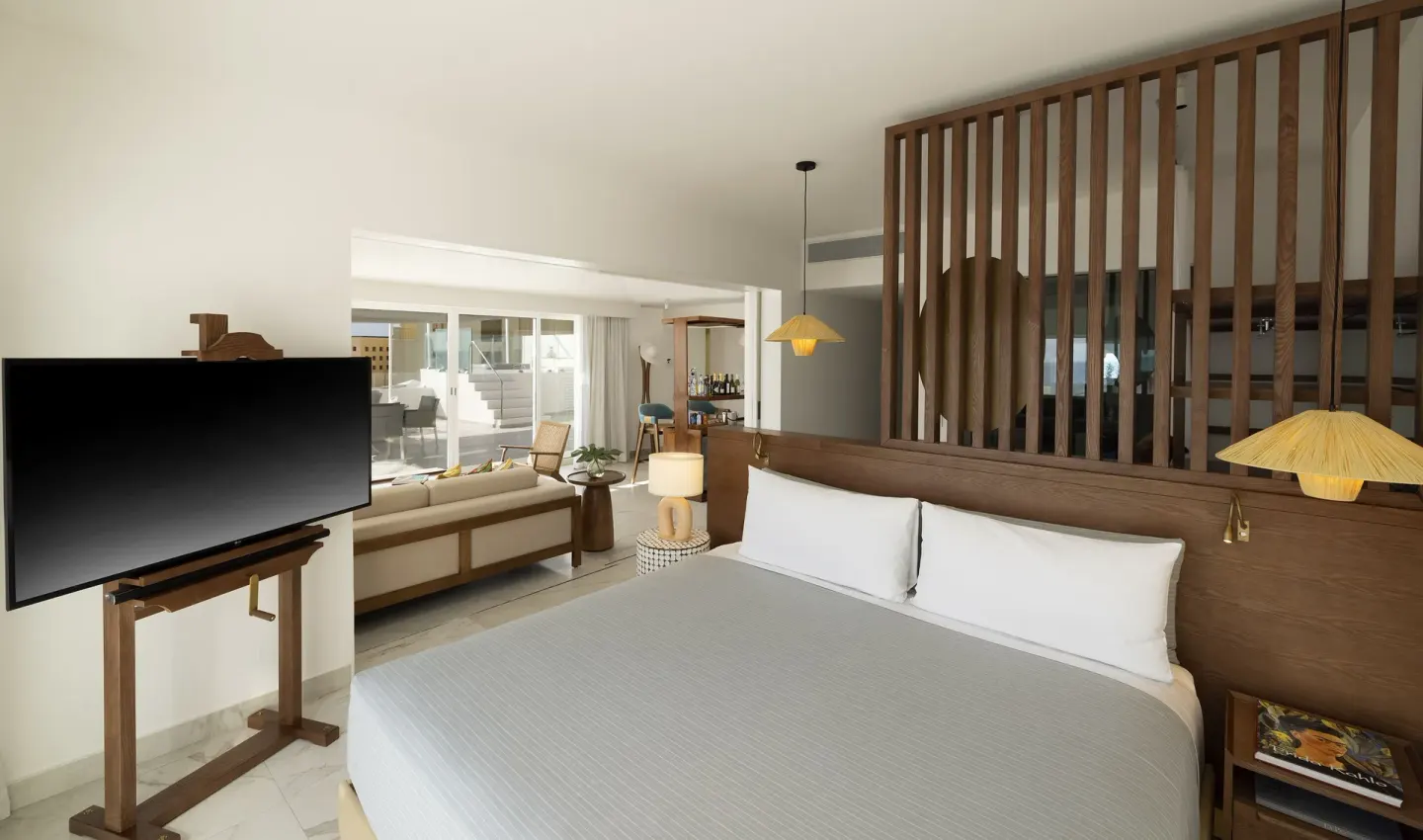 Beyond ME+ Suite king bed and living area with TV at ME Cabo.