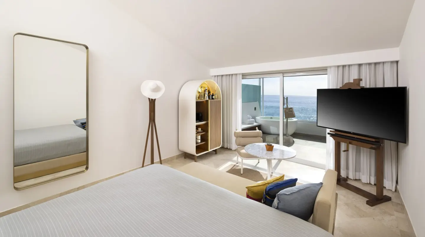 Extra ME+ Junior Suite at ME Cabo with king bed, lounge seating, TV, balcony hot tub and ocean view.
