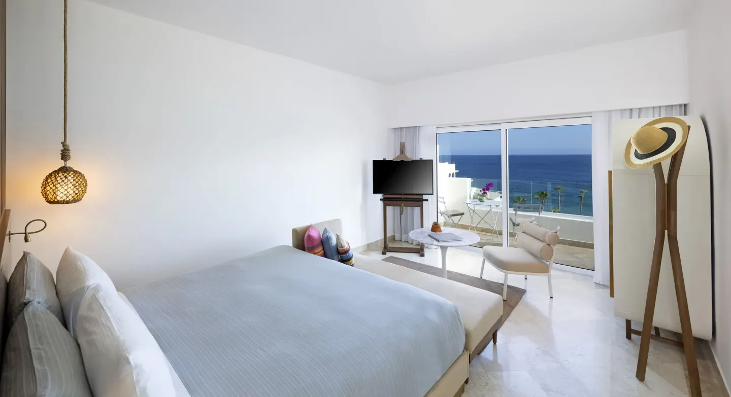 Extra ME+ Junior Suite at ME Cabo with king bed, seating area, TV and ocean-view balcony.