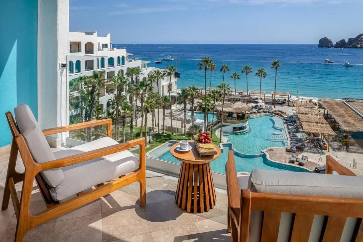 Studio ME+ Suite balcony with cushioned chairs overlooking pool and sea at ME Cabo.