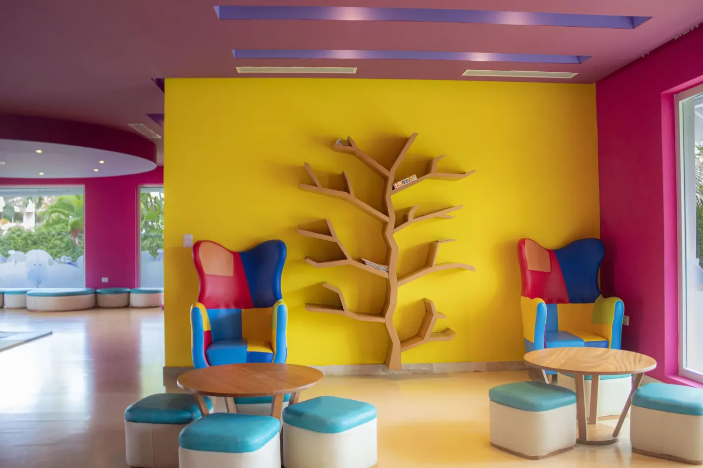 Colorful kids lounge with bright chairs and tree-shaped shelving at Melia Caribe Beach Resort.