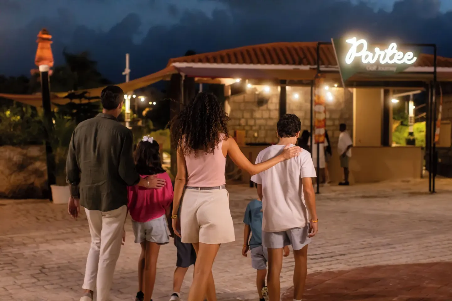 Family walking toward a lit snack stand at Melia Caribe Beach Resort.