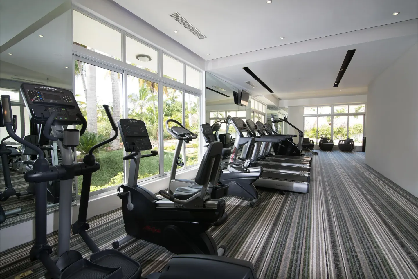 Fitness room with cardio machines and garden-facing windows at Melia Caribe Beach Resort.