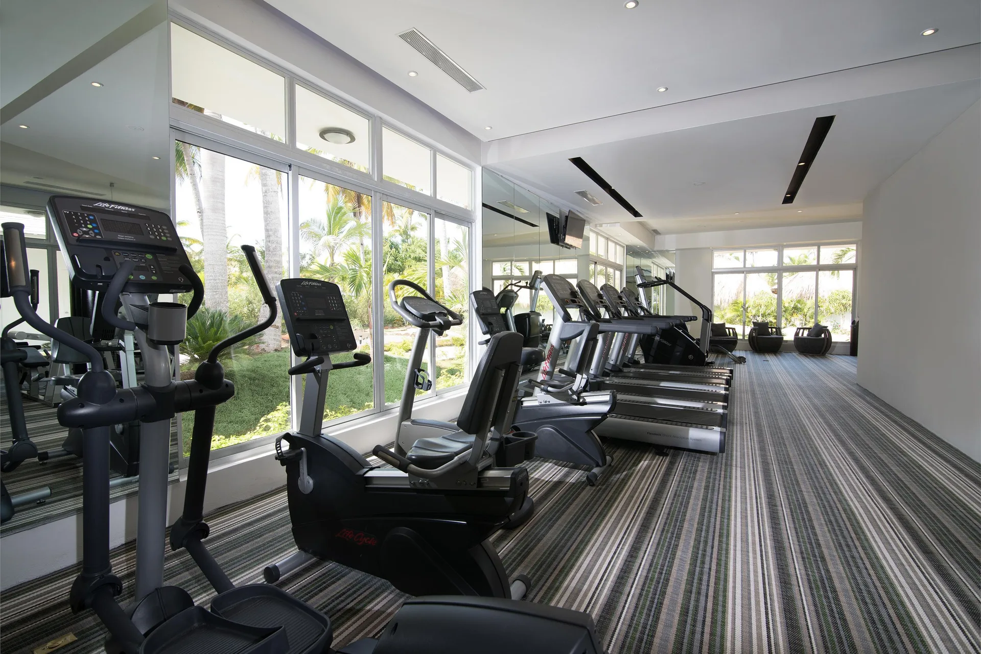 Fitness room with cardio machines and garden-facing windows at Melia Caribe Beach Resort.