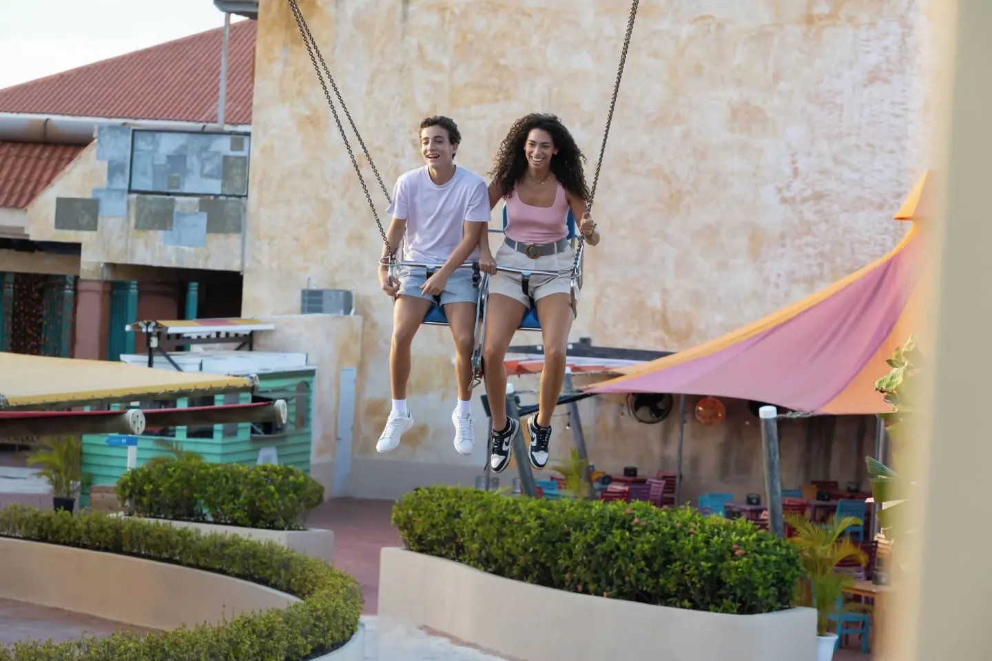 Two guests riding a large outdoor swing at Melia Caribe Beach Resort.