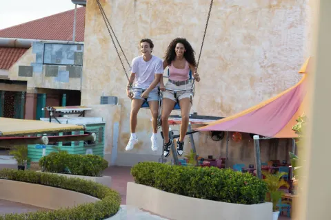 Two guests riding a large outdoor swing at Melia Caribe Beach Resort.