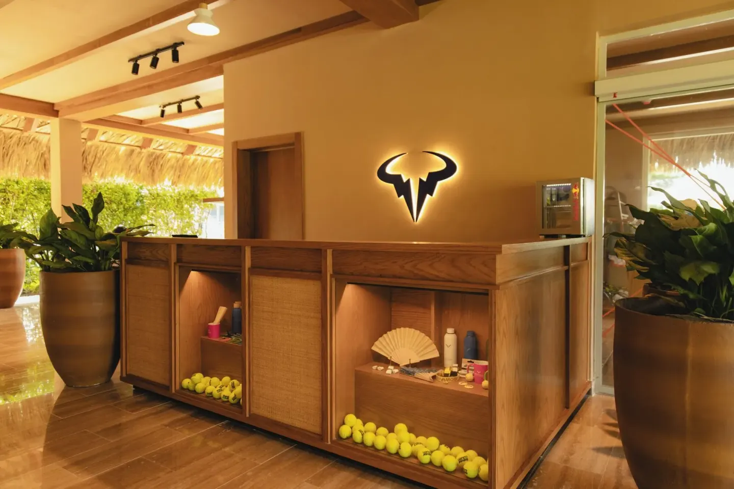 Wood tennis center reception desk with ball displays at Melia Caribe Beach Resort.
