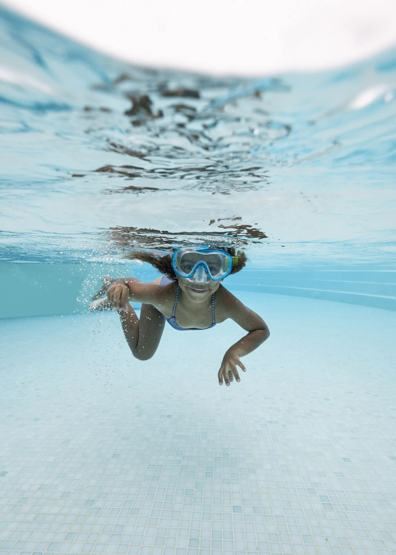 Child wearing swim goggles underwater in a pool at Melia Caribe Beach Resort.