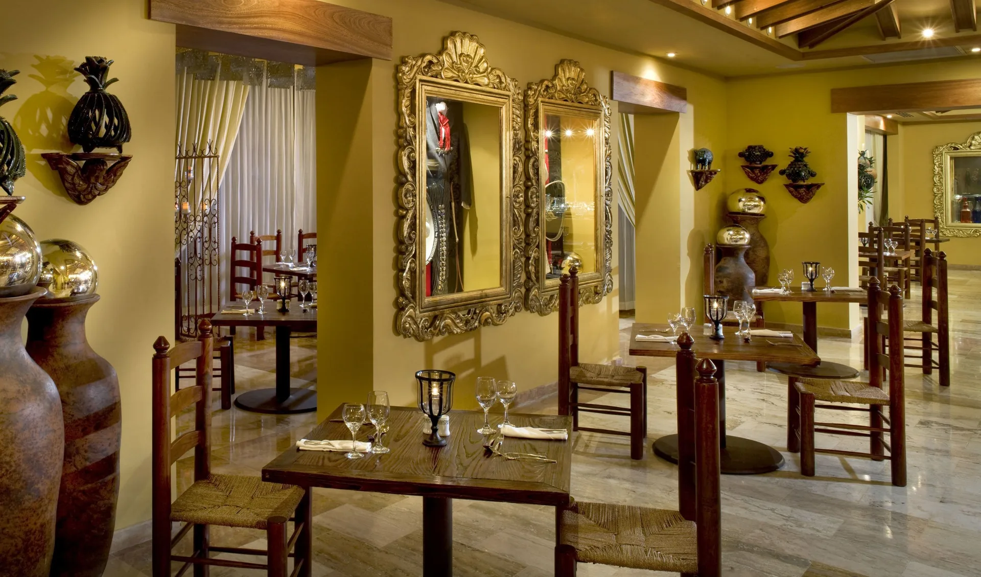 Dining tables with ornate mirrors and rustic chairs at Melia Caribe Beach Resort.