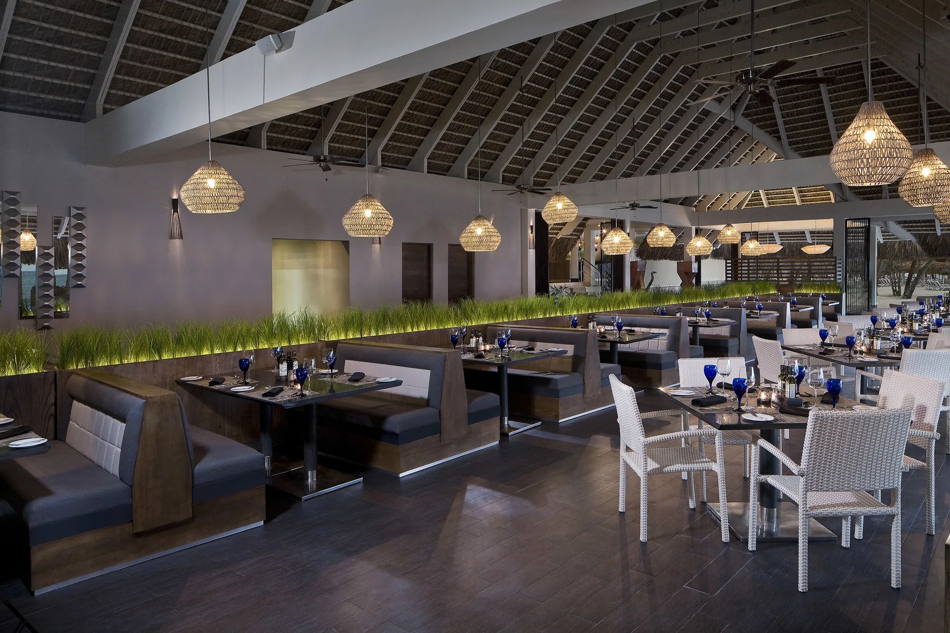 Open-air dining room with booth seating and blue glassware at Melia Caribe Beach Resort.