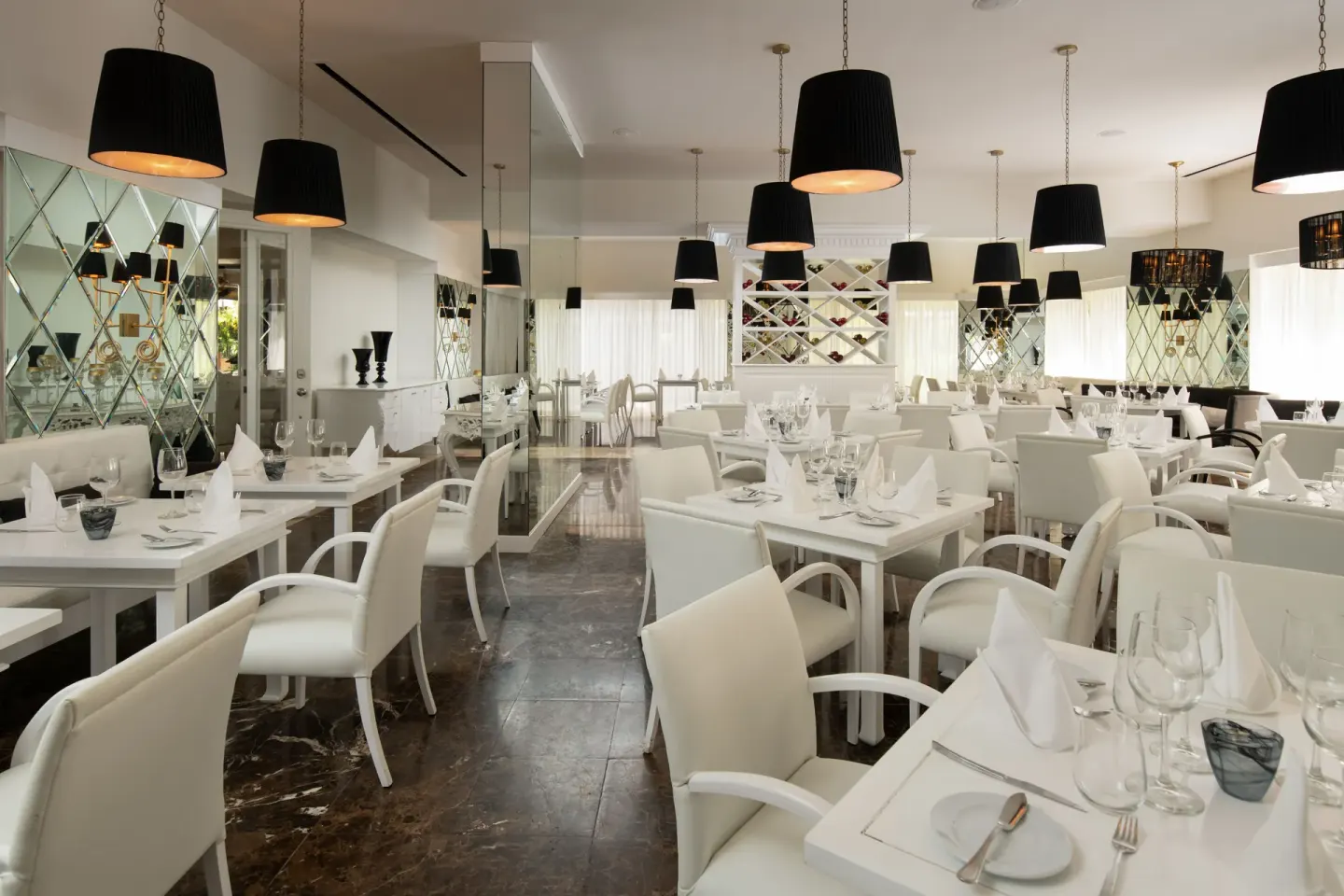 White dining room with black pendant lights and wine display at Melia Caribe Beach Resort.