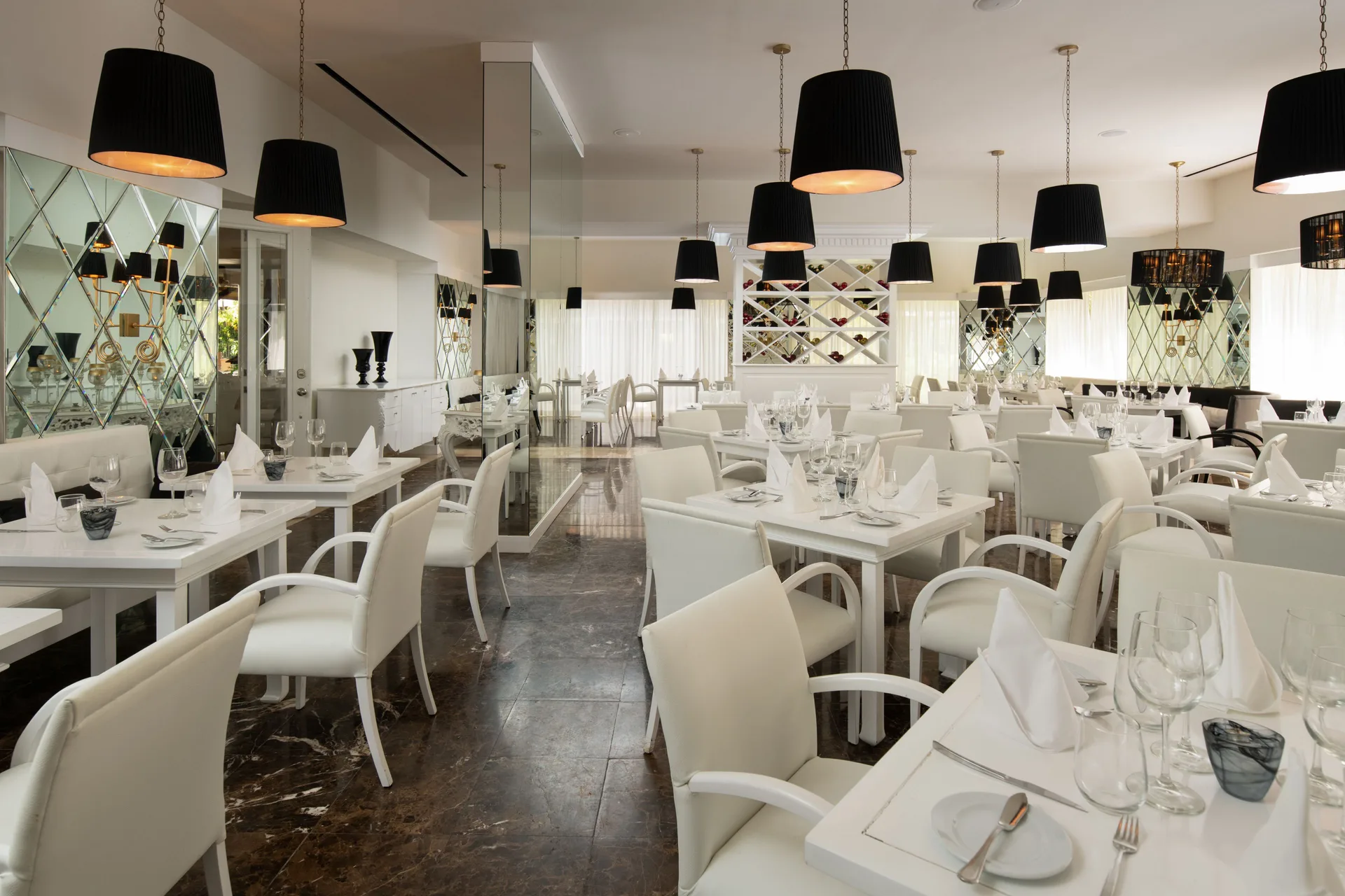 White dining room with black pendant lights and wine display at Melia Caribe Beach Resort.