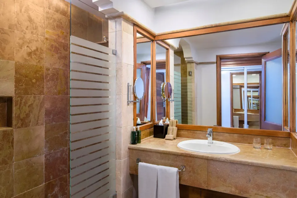 Bathroom vanity and glass shower in The Level Junior Suite Garden View at Melia Caribe Beach Resort.
