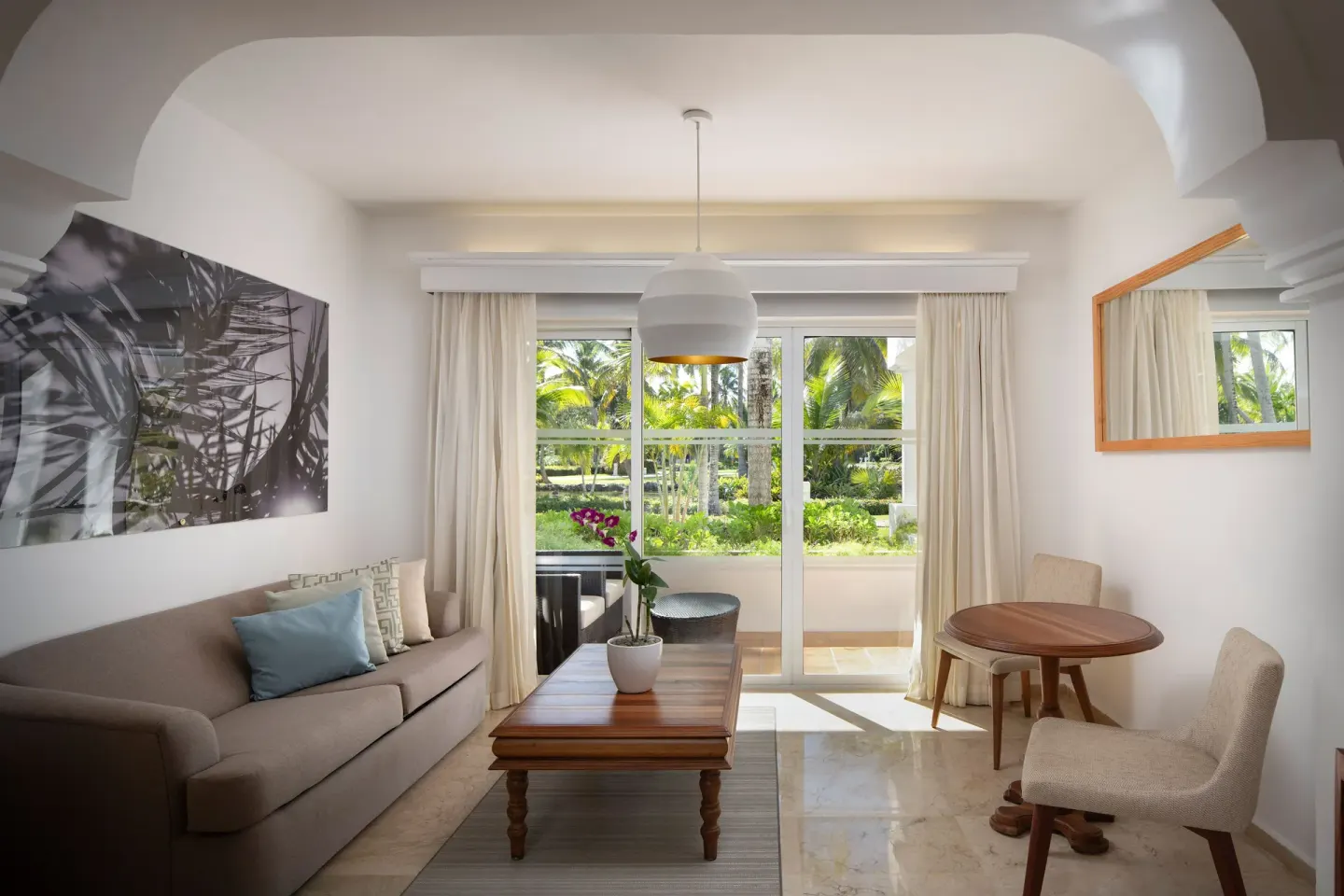 Living area with sofa, table, and balcony doors in The Level Junior Suite Garden View at Melia Caribe Beach Resort.