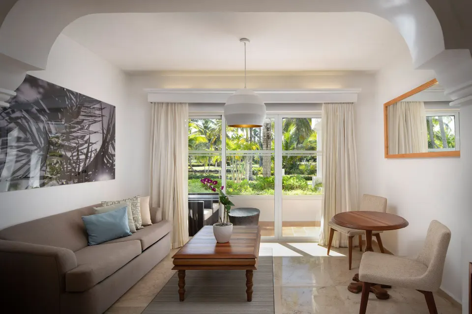 Living area with sofa, table, and balcony doors in The Level Junior Suite Garden View at Melia Caribe Beach Resort.