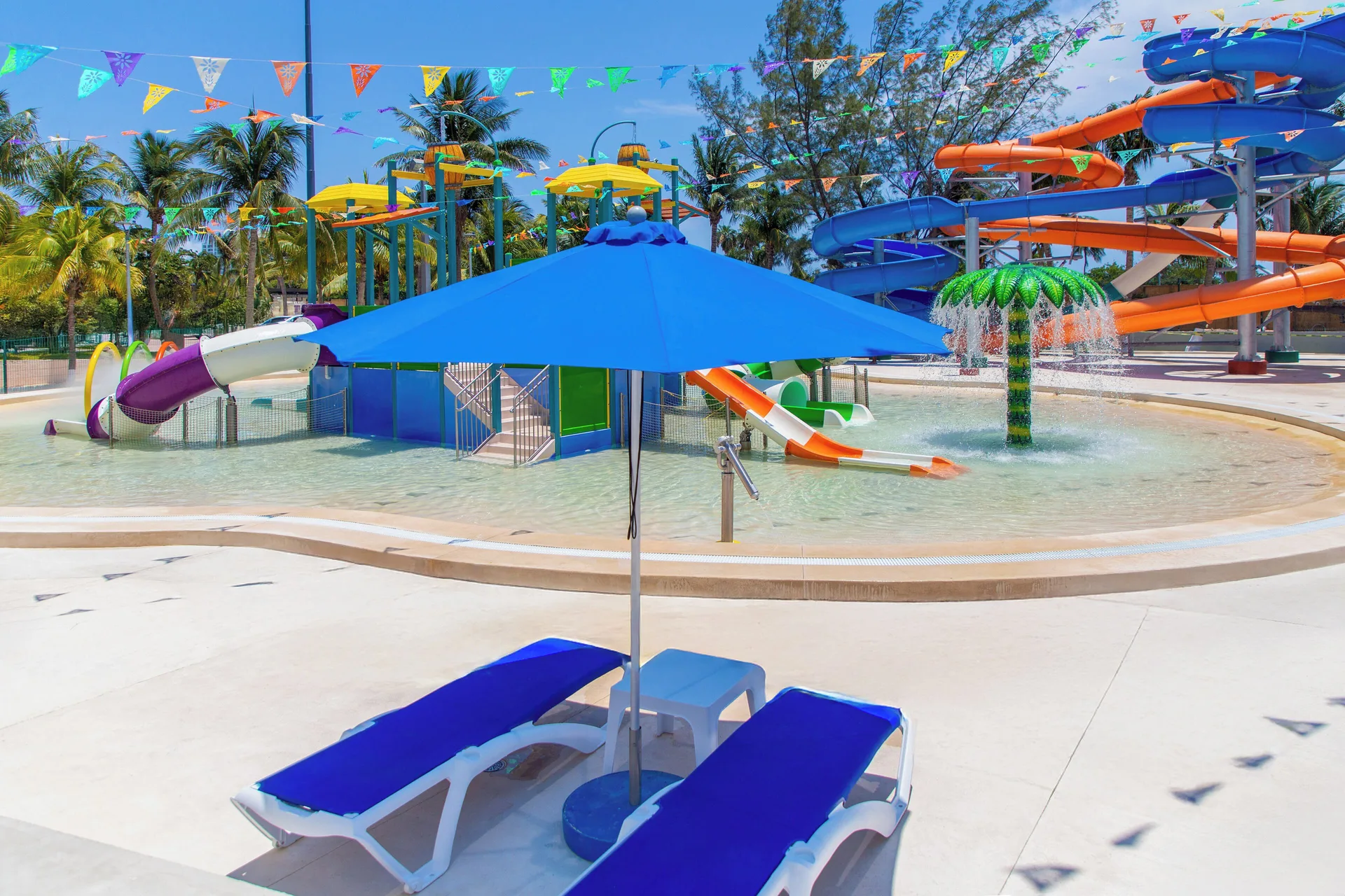 Children's splash pool with slides and blue loungers at Melia Casa Maya Cancun.