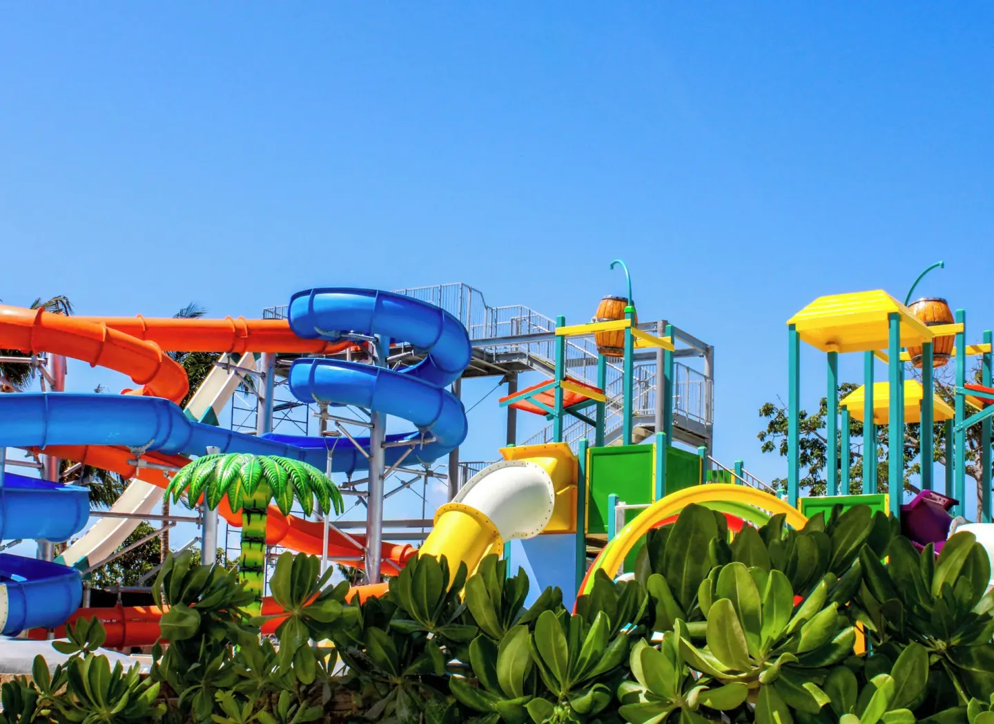 Colorful water slides and play towers behind tropical greenery at Melia Casa Maya Cancun.