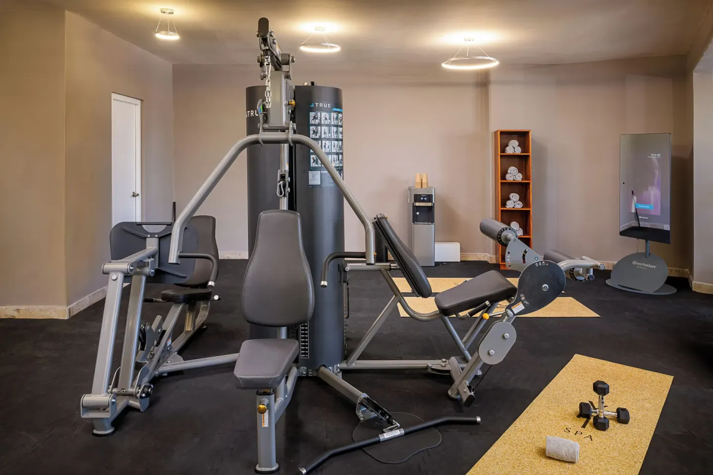Fitness room with weight machines, mats, towels, and a water station at Melia Casa Maya Cancun.