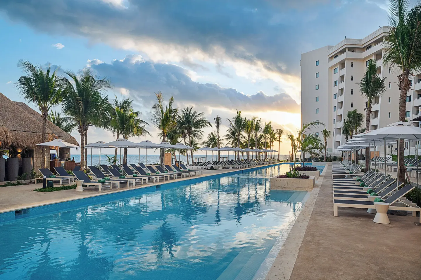 Main pool with loungers and palms at Melia Casa Maya Cancun near the beach at sunset.