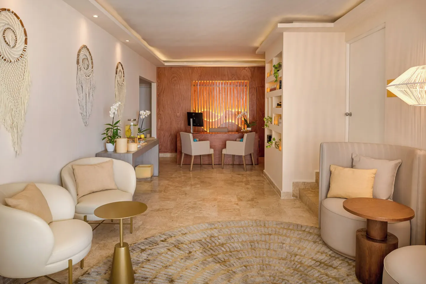 Spa reception lounge with cream seating, wood desk, and woven wall decor at Melia Casa Maya Cancun.