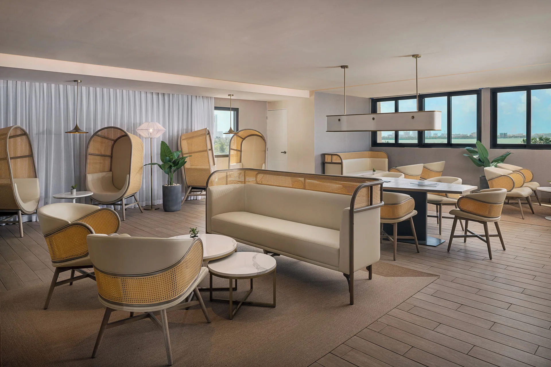 A bright lounge with sofas, cane chairs, and windows at Melia Casa Maya Cancun.