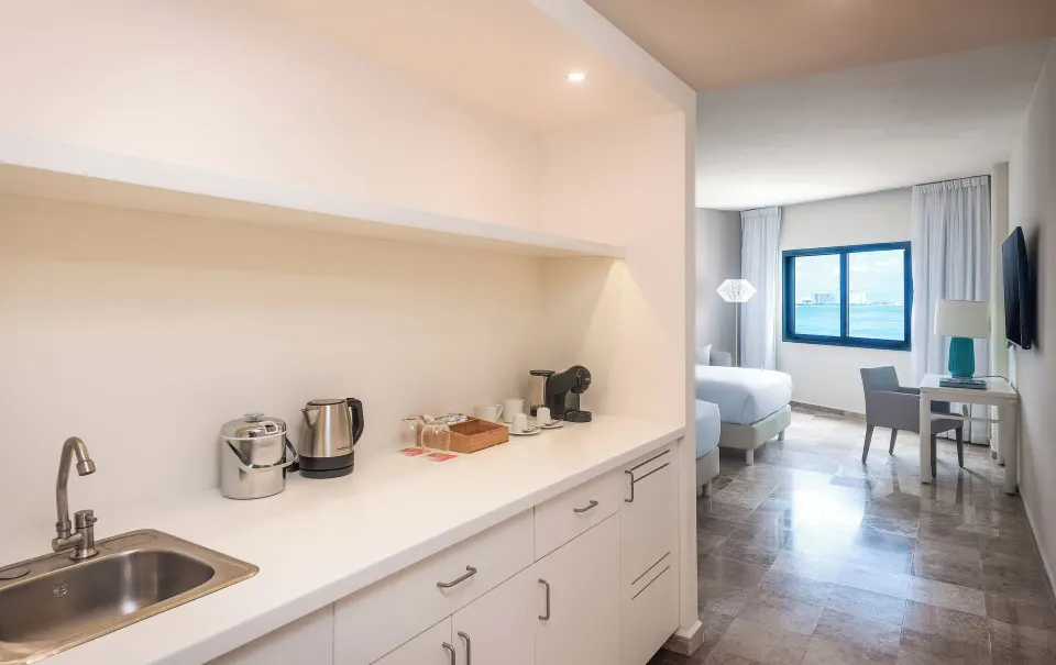 The Level Grand Suite kitchenette with sink, coffee station, and bedroom beyond at Melia Casa Maya Cancun.